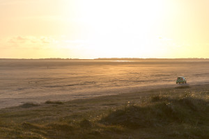 Auto auf dem Strand beim Sonnenuntergang