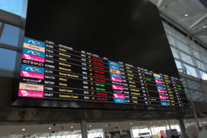 Sehr bunte Abflugtafel Sydney Flughafen